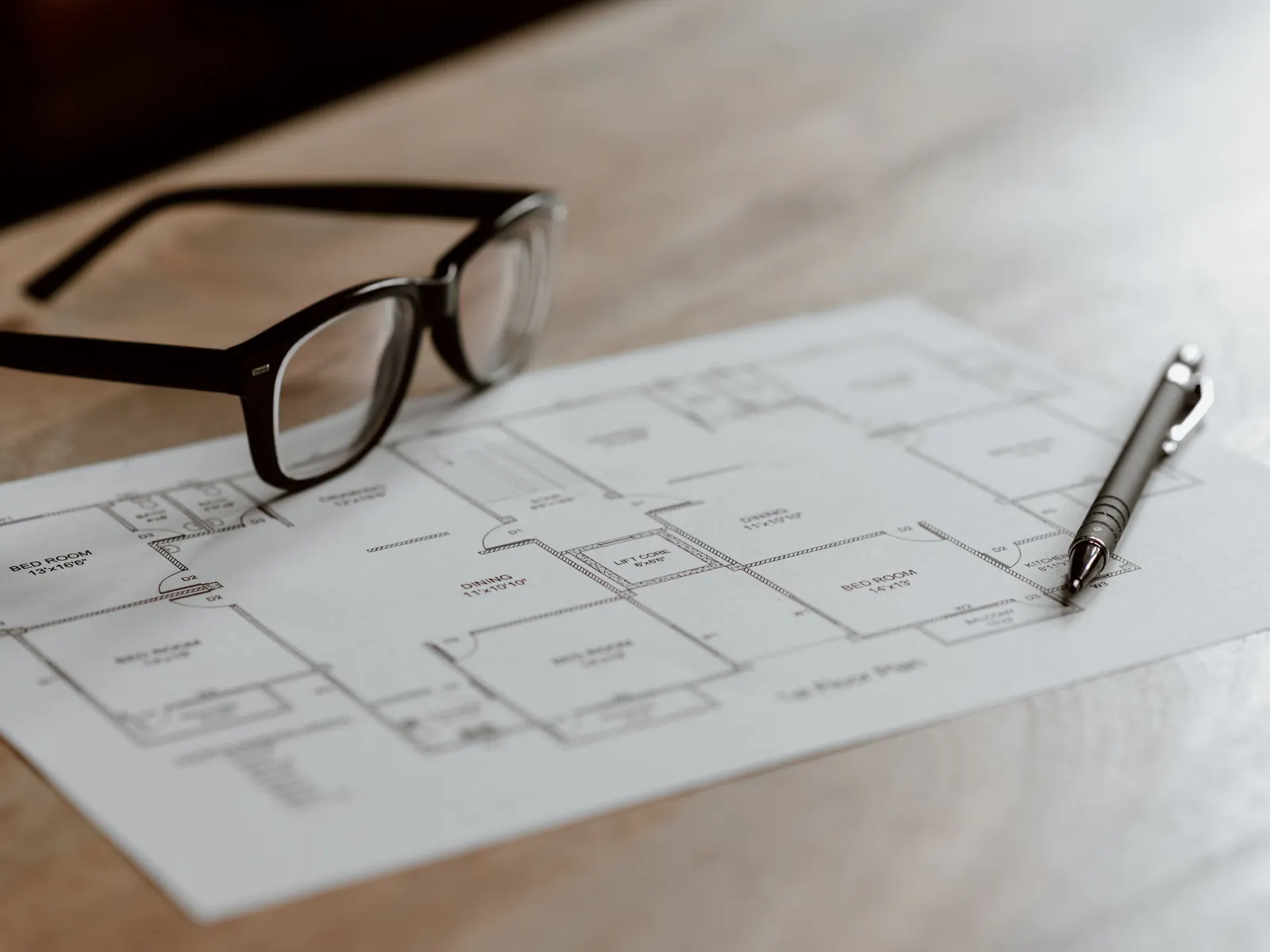 Glasses and a pen resting on a printed house floor plan